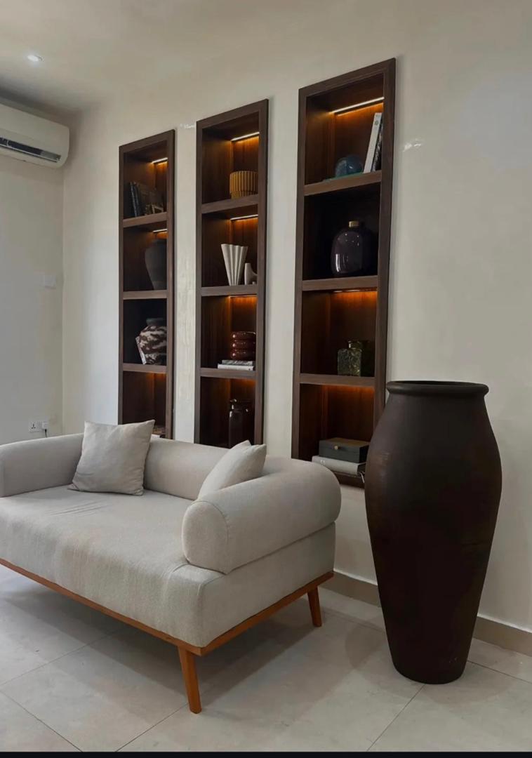 Styled living room with illuminated shelving, ceramic decor and floor vase